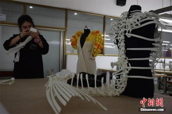 4月11日,在武汉纺织大学服装与服饰设计专业毕业作品展上,3套用3D技术打印而成的服装作品一经亮相,引来不少关注。据设计者汤晓介绍,该服装以希腊神话故事里海妖Siren为灵感而创作,3D服装立体呈现出了海妖的骨骼结构。服装从设计到成型用时4个月,耗资5万余元。图为汤晓在组装3D服装。